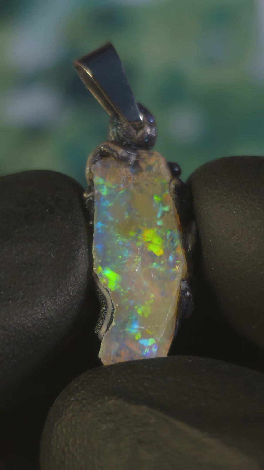 Video: raw uncut Ethiopian Welo opal pendant. Colour: blue and green, vivid. Body: transparent. Held in a gloved hand against a dark background.