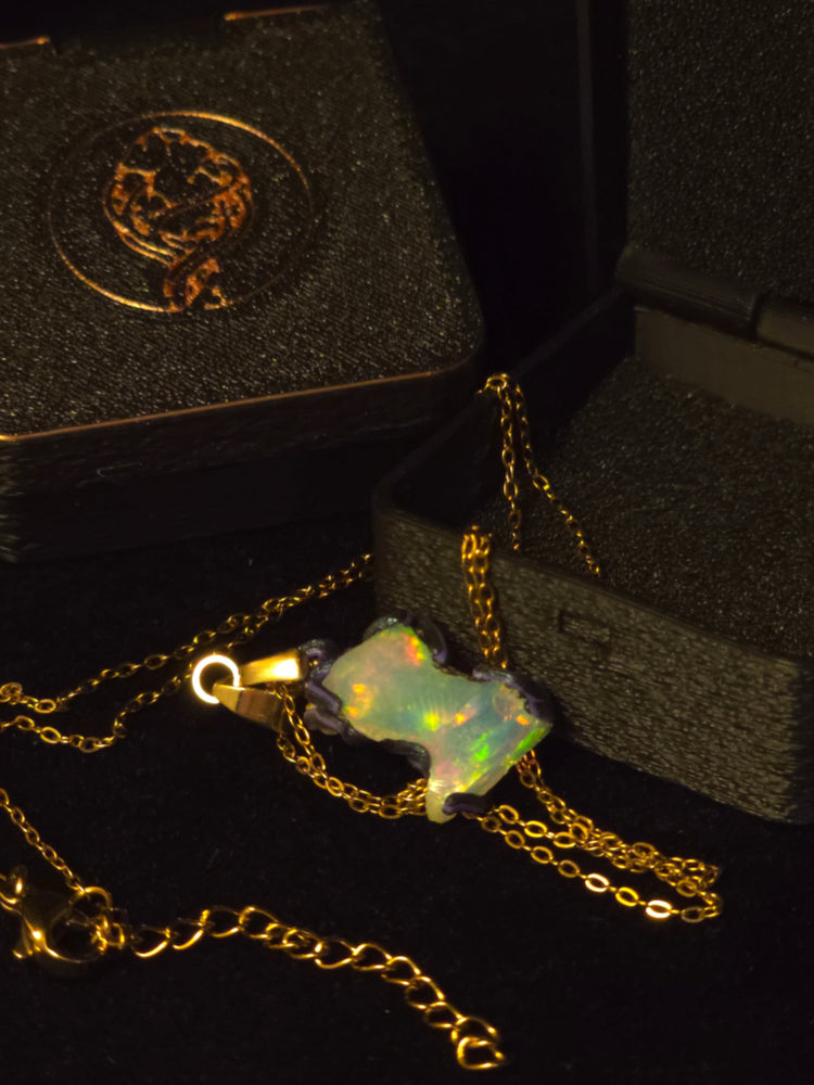 Raw uncut Ethiopian Welo opal pendant, every colour at once, blue body. Shown with its open gift box.