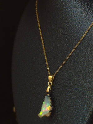 Raw uncut Ethiopian Welo opal pendant, green flashes on light blue. Worn on a black display bust.