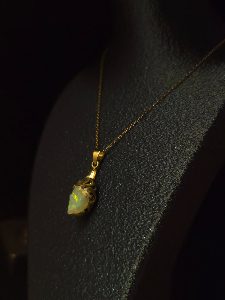 Video: raw uncut Ethiopian Welo opal pendant. Colour: green and red, strong. Body: light blue. Lying on a dark surface.