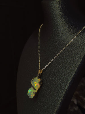 Raw uncut Ethiopian Welo opal pendant, shifting rainbow fire. Worn on a black display bust.