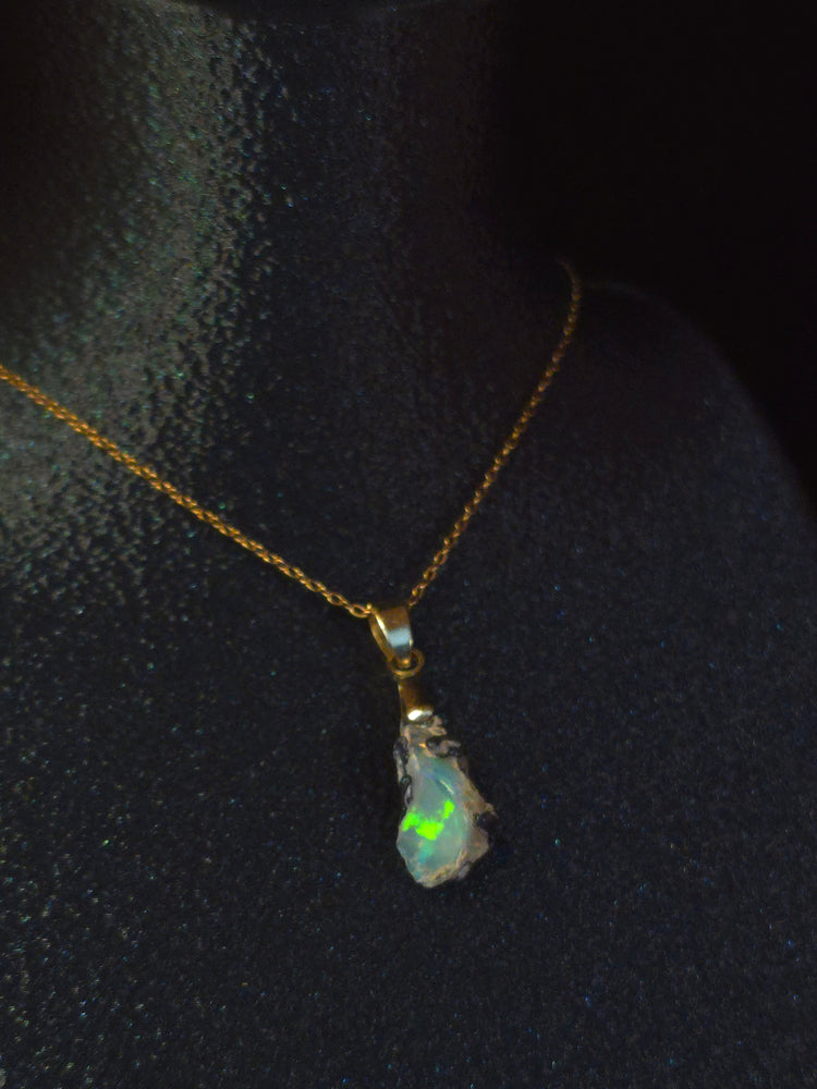 Video: raw uncut Ethiopian Welo opal pendant. Colour: blue and green, strong. Body: deep blue. Lying on a dark surface.